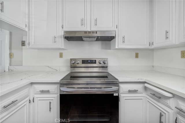 kitchen with light stone counters, under cabinet range hood, white cabinets, and stainless steel electric range oven