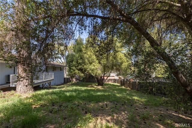 view of yard featuring central air condition unit, fence, and a wooden deck