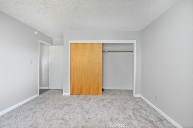 unfurnished bedroom featuring baseboards, carpet, a closet, and a textured ceiling