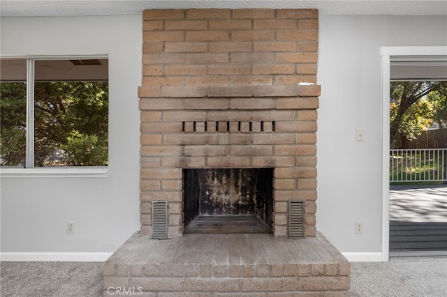 interior details featuring carpet flooring, a brick fireplace, a textured ceiling, baseboards, and visible vents
