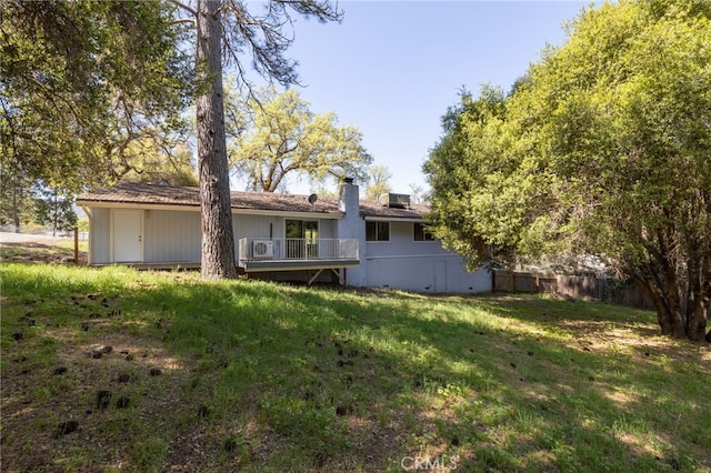 rear view of house featuring a lawn, fence, and a chimney
