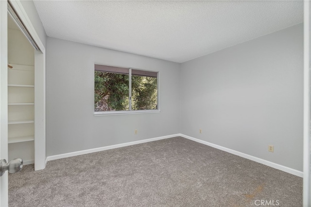 unfurnished bedroom with a textured ceiling, baseboards, carpet, and a closet