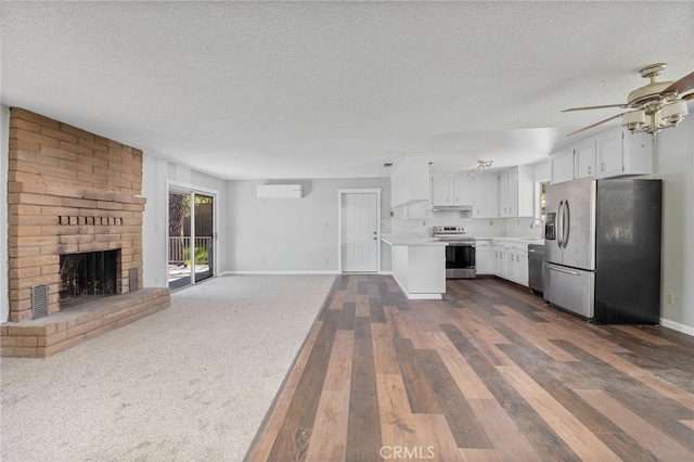 unfurnished living room featuring a textured ceiling, a wall mounted AC, baseboards, and a fireplace