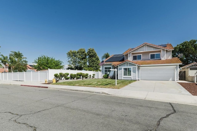 view of front of property featuring fence, a front yard, roof mounted solar panels, driveway, and a tile roof