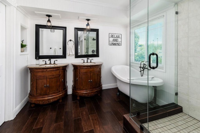 full bath featuring a freestanding bath, vanity, ornamental molding, and wood finished floors