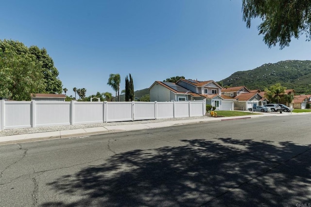 view of street with a mountain view, a residential view, sidewalks, and curbs