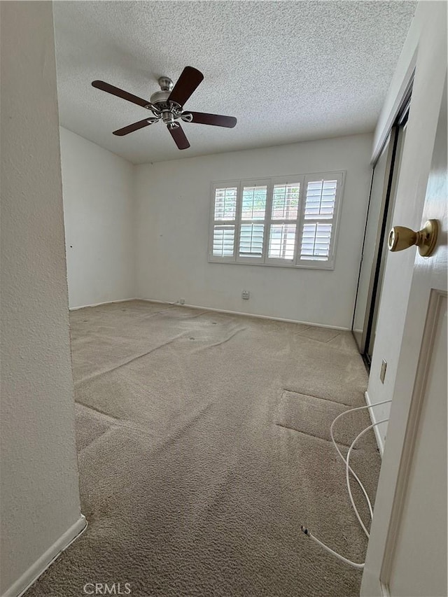 carpeted spare room featuring a textured ceiling and ceiling fan