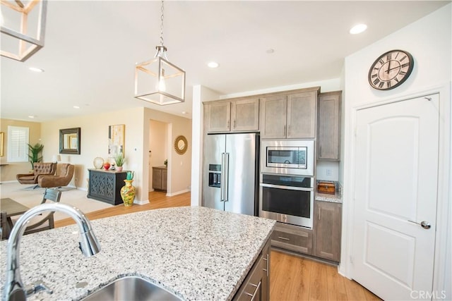 11534 Alana Ln, Beaumont, CA 92223 - kitchen with light wood finished floors, stainless steel appliances, a sink, open floor plan, and light stone countertops