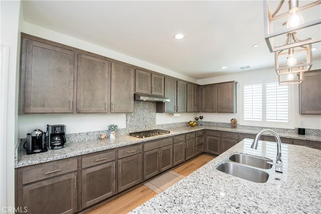 11534 Alana Ln, Beaumont, CA 92223 - kitchen featuring a sink, stainless steel gas stovetop, light wood-style floors, dark brown cabinetry, and under cabinet range hood