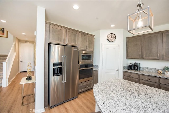 11534 Alana Ln, Beaumont, CA 92223 - kitchen with appliances with stainless steel finishes, light stone counters, hanging light fixtures, and light wood-style flooring