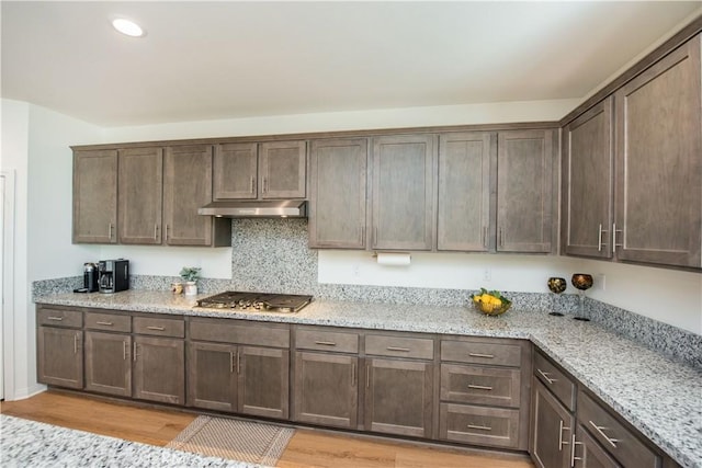 11534 Alana Ln, Beaumont, CA 92223 - kitchen featuring light wood finished floors, stainless steel gas cooktop, dark brown cabinets, light stone counters, and under cabinet range hood