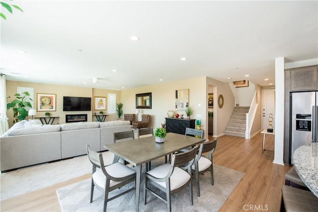 11534 Alana Ln, Beaumont, CA 92223 - dining room with a glass covered fireplace, recessed lighting, light wood-style floors, and stairway
