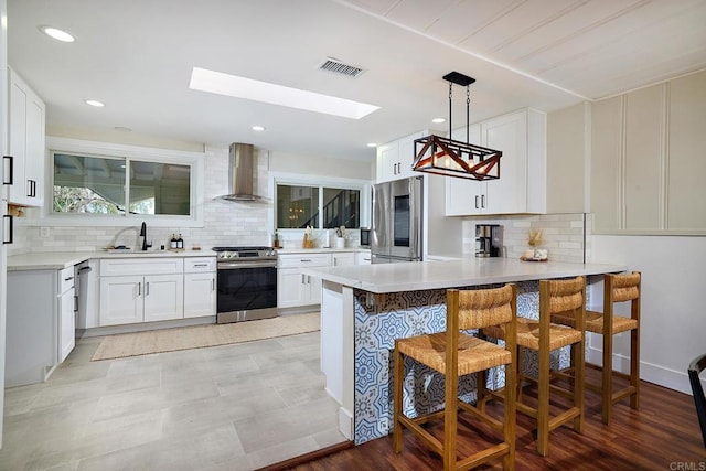 1105 Fulton Rd, San Marcos, CA 92069 - kitchen featuring wall chimney exhaust hood, a peninsula, a sink, visible vents, and appliances with stainless steel finishes