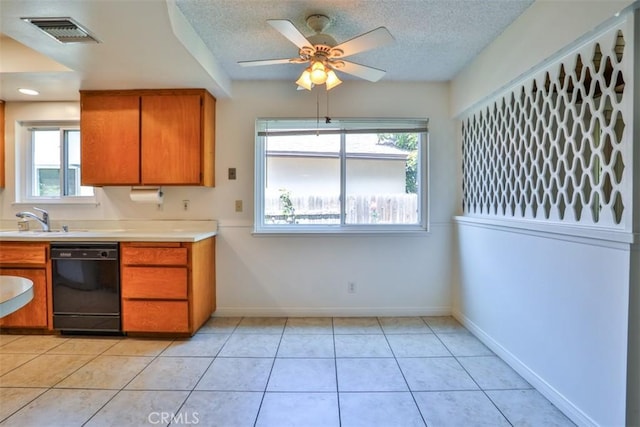 kitchen with a sink, dishwasher, brown cabinetry, a wealth of natural light, and visible vents