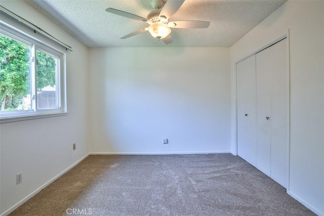 unfurnished bedroom with carpet floors, a textured ceiling, a ceiling fan, baseboards, and a closet