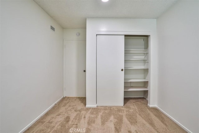 unfurnished bedroom with carpet, a closet, a textured ceiling, and visible vents