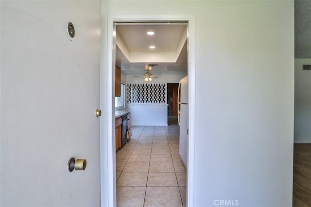 corridor with visible vents, baseboards, recessed lighting, a raised ceiling, and light tile patterned floors
