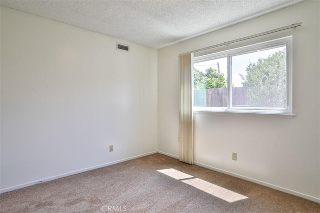 empty room with visible vents, a textured ceiling, carpet floors, and baseboards
