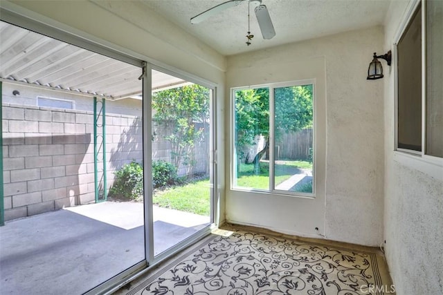 doorway to outside featuring ceiling fan and a textured ceiling
