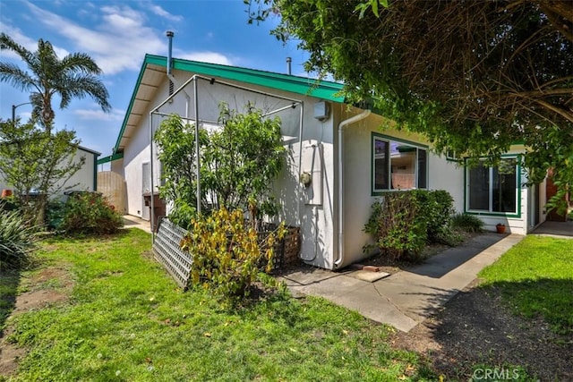 view of side of property featuring a lawn and stucco siding