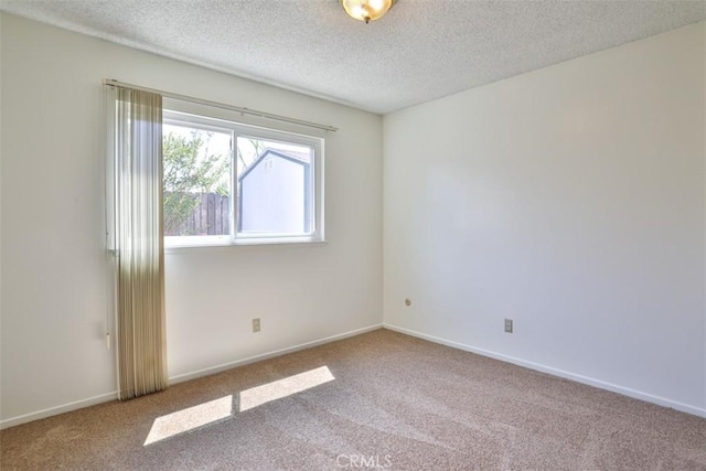 spare room featuring baseboards, carpet, and a textured ceiling