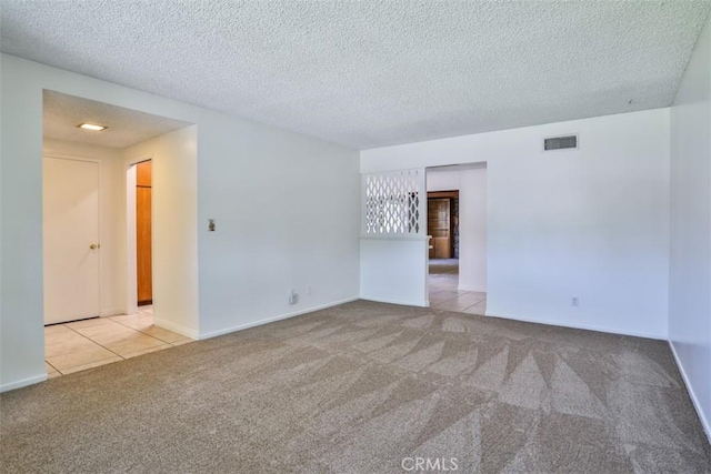 tiled empty room featuring baseboards, carpet, a textured ceiling, and visible vents