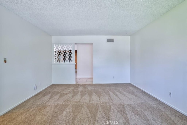 empty room featuring carpet floors, baseboards, a textured ceiling, and visible vents