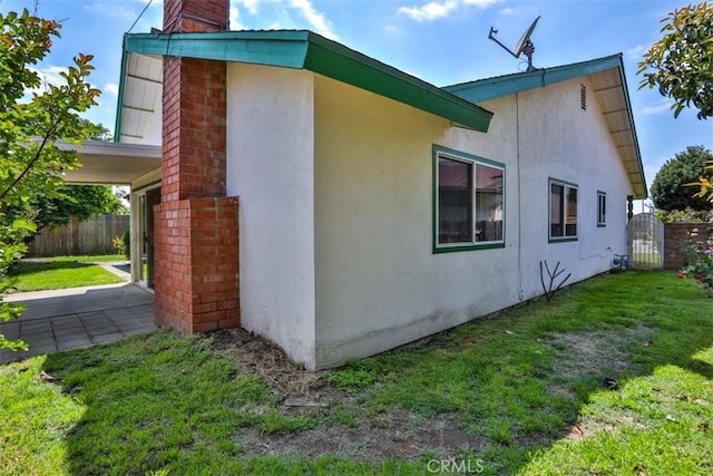 view of property exterior featuring a lawn, fence, a chimney, and stucco siding