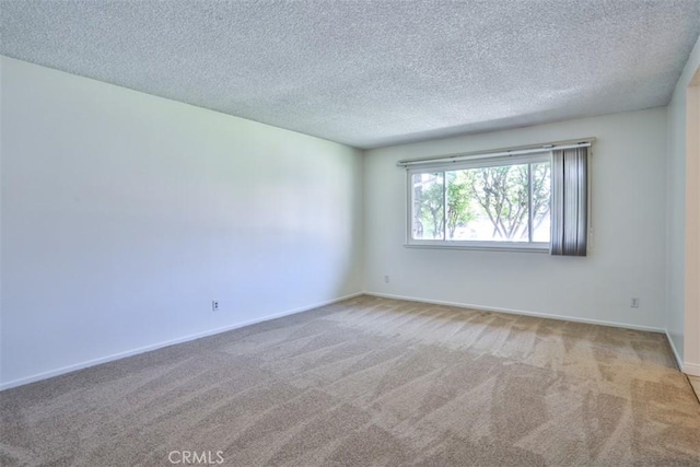 carpeted spare room with a textured ceiling and baseboards