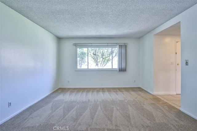 carpeted spare room with baseboards and a textured ceiling