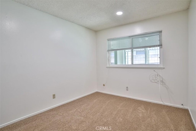 empty room with baseboards, a textured ceiling, carpet, and recessed lighting