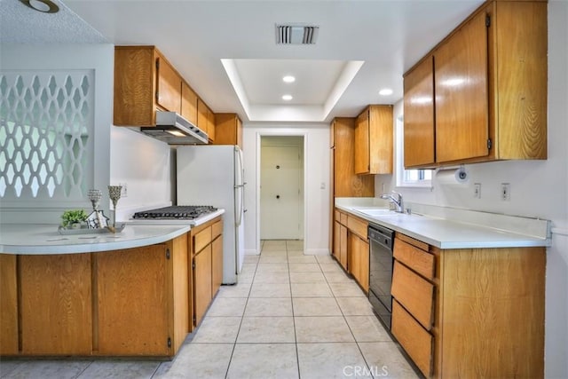 kitchen with visible vents, light countertops, under cabinet range hood, a sink, and dishwasher
