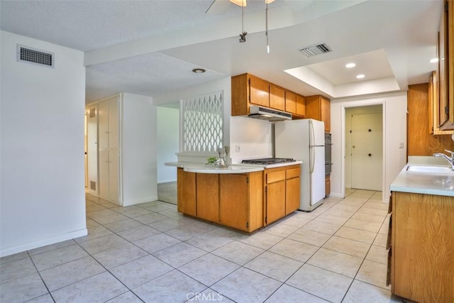 kitchen with visible vents, a sink, under cabinet range hood, and light countertops