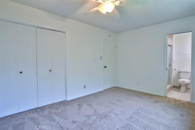 unfurnished bedroom featuring ceiling fan, carpet floors, a textured ceiling, ensuite bathroom, and a closet