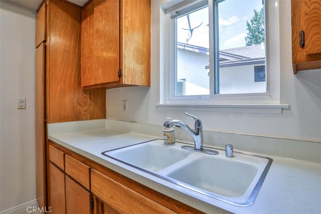 kitchen with a sink, light countertops, and brown cabinetry
