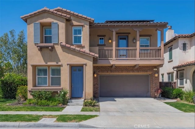 view of front of home featuring a garage, a balcony, driveway, a tiled roof, and stucco siding