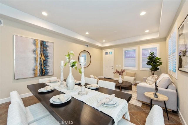 dining room with a raised ceiling, visible vents, baseboards, recessed lighting, and dark tile patterned floors