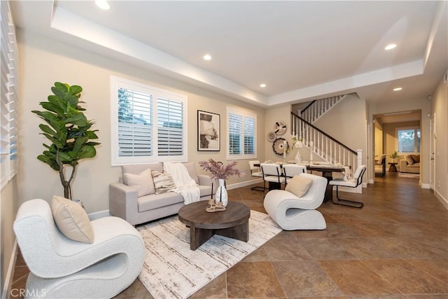living area with baseboards, recessed lighting, a raised ceiling, and stairs