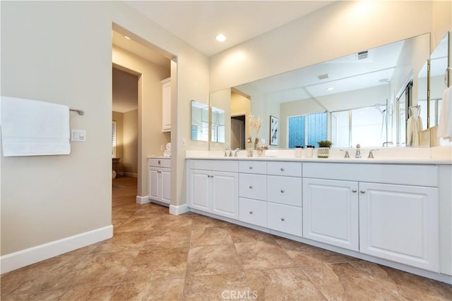 full bath with double vanity, a sink, visible vents, and baseboards