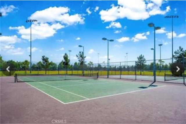 view of tennis court with community basketball court and fence
