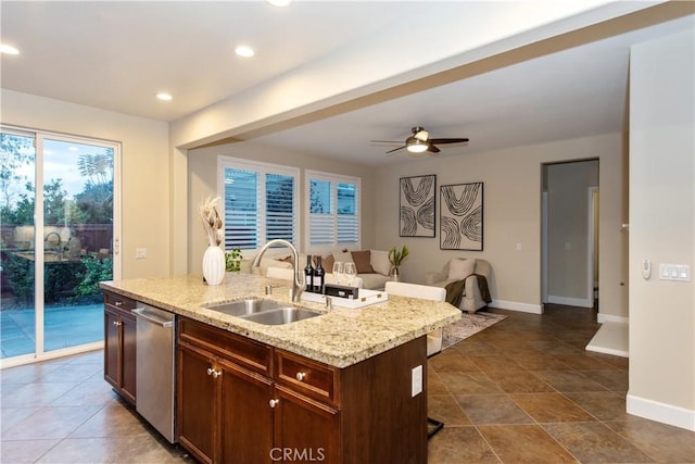 kitchen with stainless steel dishwasher, a sink, open floor plan, and a healthy amount of sunlight