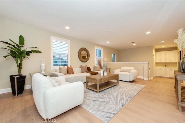 living area with baseboards, light wood-type flooring, and recessed lighting