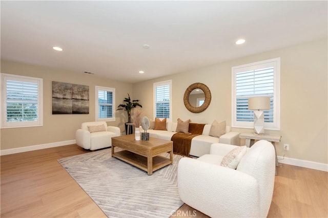 living area featuring plenty of natural light, light wood-style flooring, and baseboards