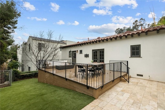 back of house with stucco siding, a tile roof, fence, and a yard