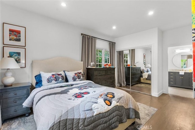 bedroom with recessed lighting, wood finished floors, a closet, and ensuite bath
