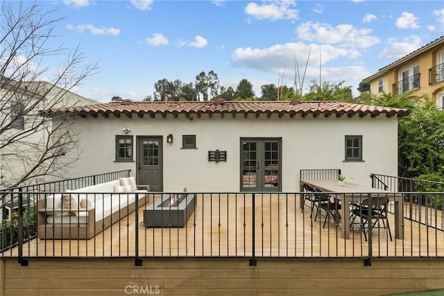 wooden terrace with an outdoor living space, outdoor dining space, and french doors