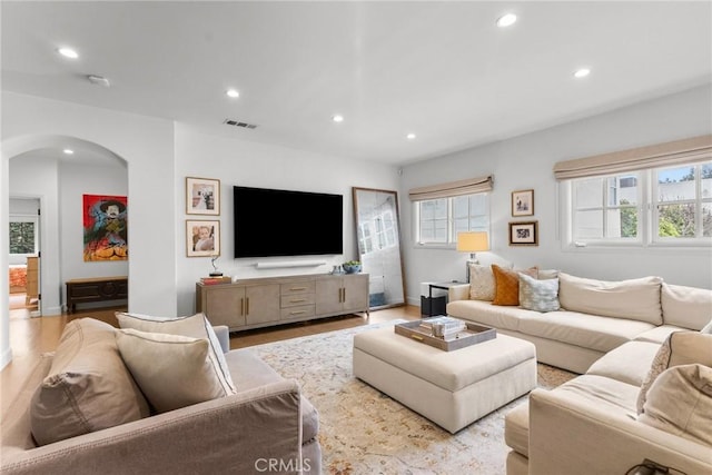 living area featuring plenty of natural light, arched walkways, and recessed lighting