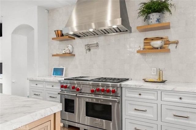 kitchen with open shelves, wall chimney range hood, double oven range, and decorative backsplash