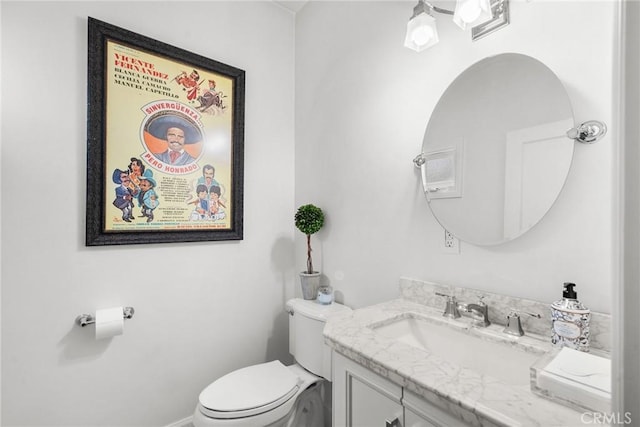 half bathroom featuring toilet, vanity, and baseboards