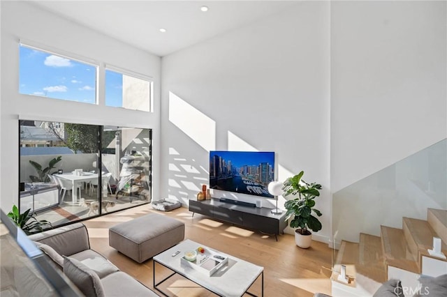 living room with stairs, recessed lighting, a towering ceiling, and wood finished floors